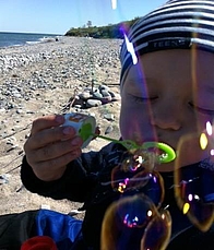 Kind am Strand macht Seifenblasen